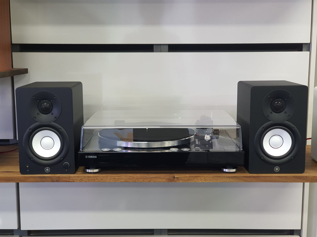 Turntable with black speakers on a wooden shelf against a white wall