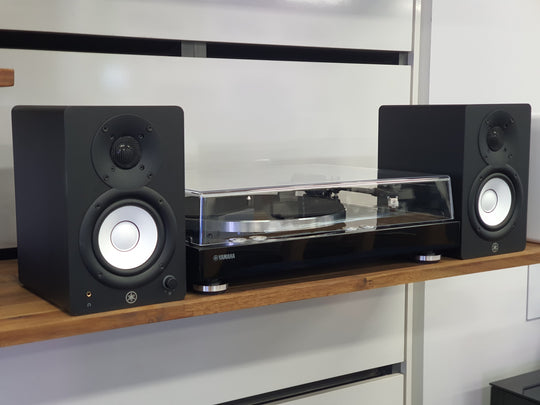 Black speakers on a wooden shelf with a turntable in the center.