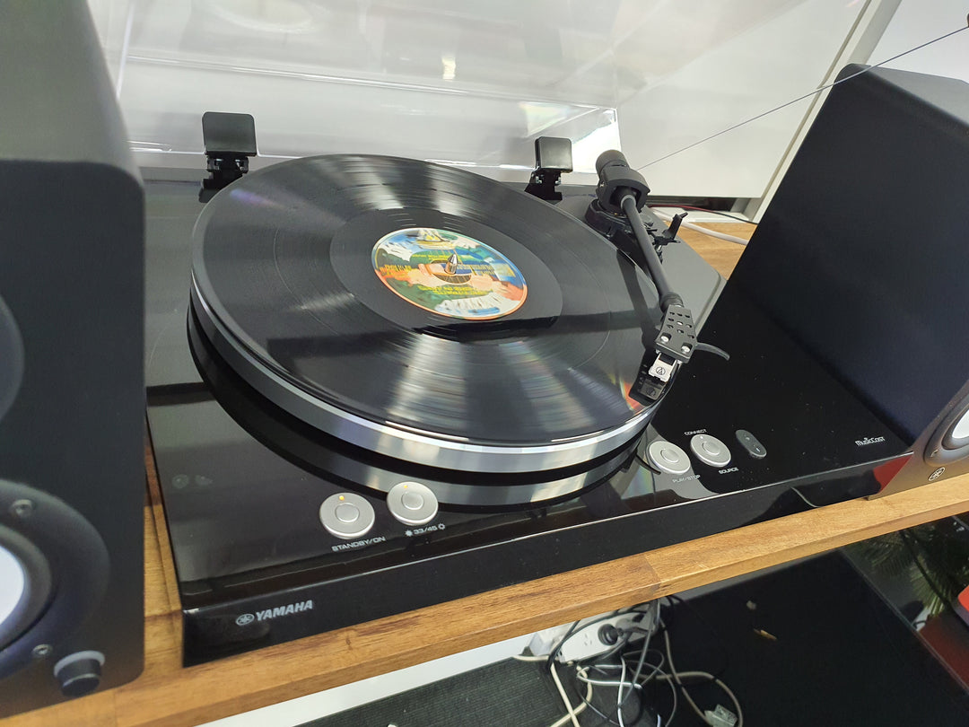 Yamaha Turntable with a vinyl record on a wooden turntable stand.