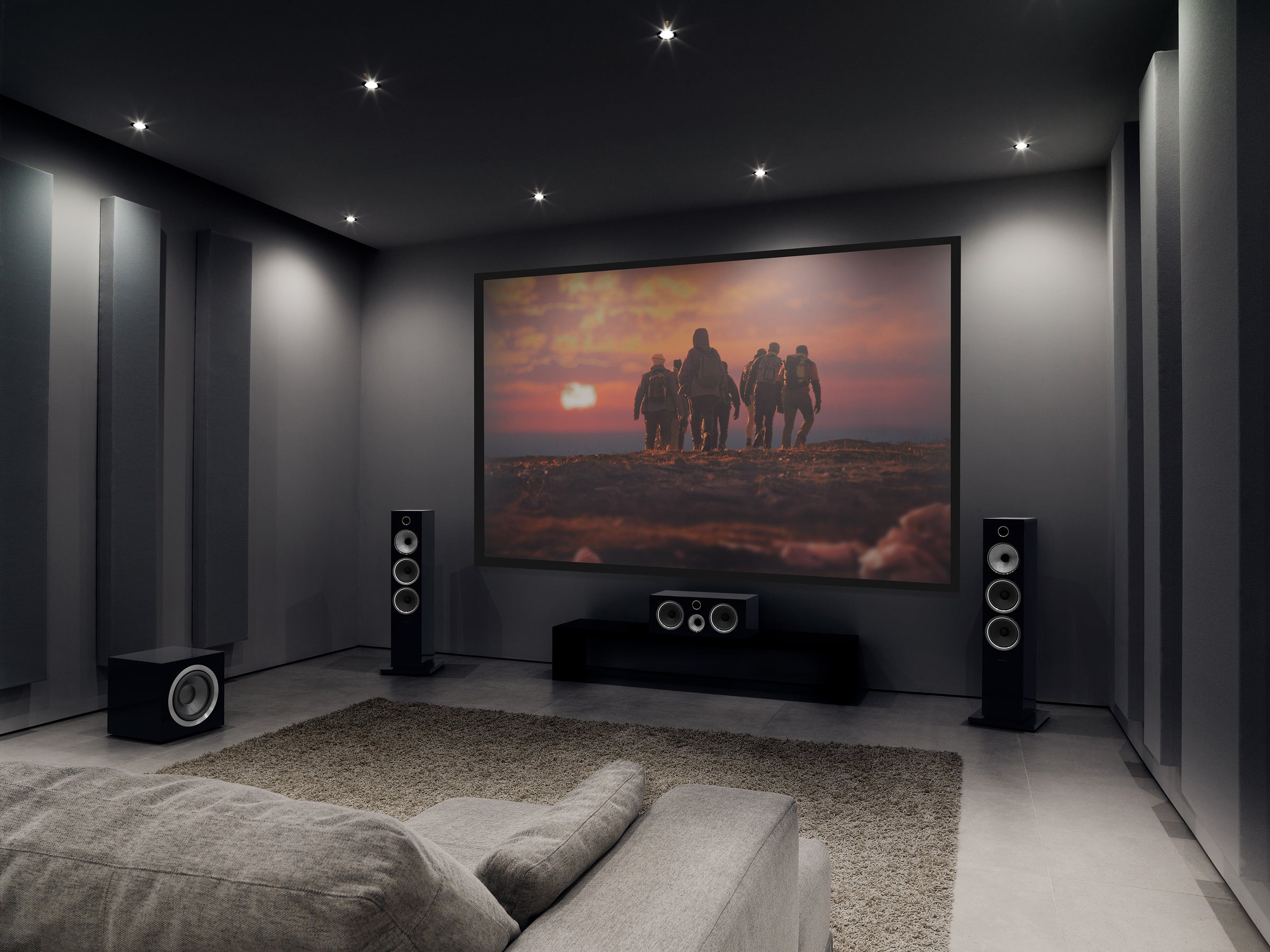 A home theatre audio system setup featuring a projector, floor standing speakers and centre speaker complete with a couch and rug in the foreground