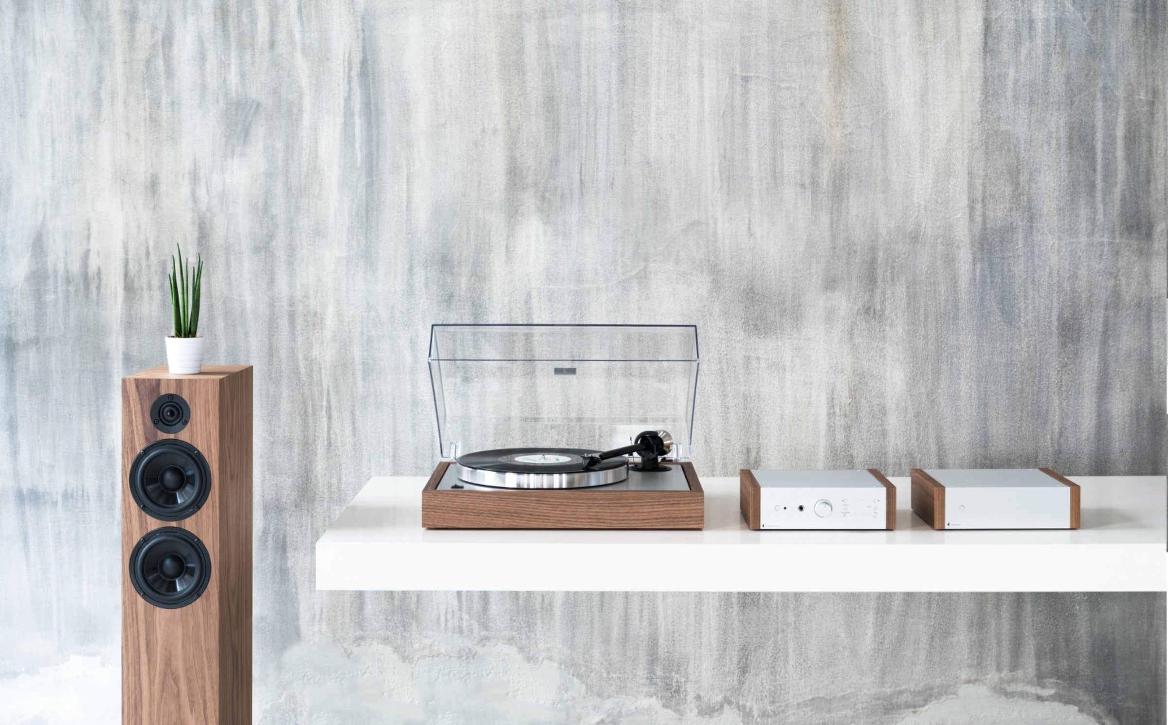 A record player and turntable setup on a white floating table, featuring the Pro-Ject MaiA DS2 Integrated Amplifier with Bluetooth, Pro-Ject Phono Box DS2 and Pro-Ject Primary E Turntable with OM Cartridge. 