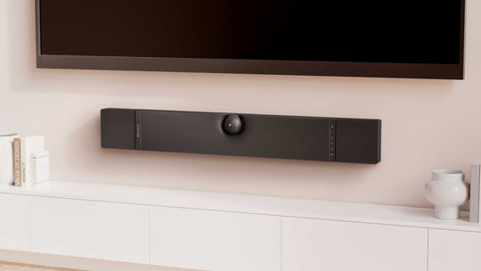 The DEVIALET Dione Soundbar with Dolby ATMOS in black installed on a wall above a tv unit and below the tv