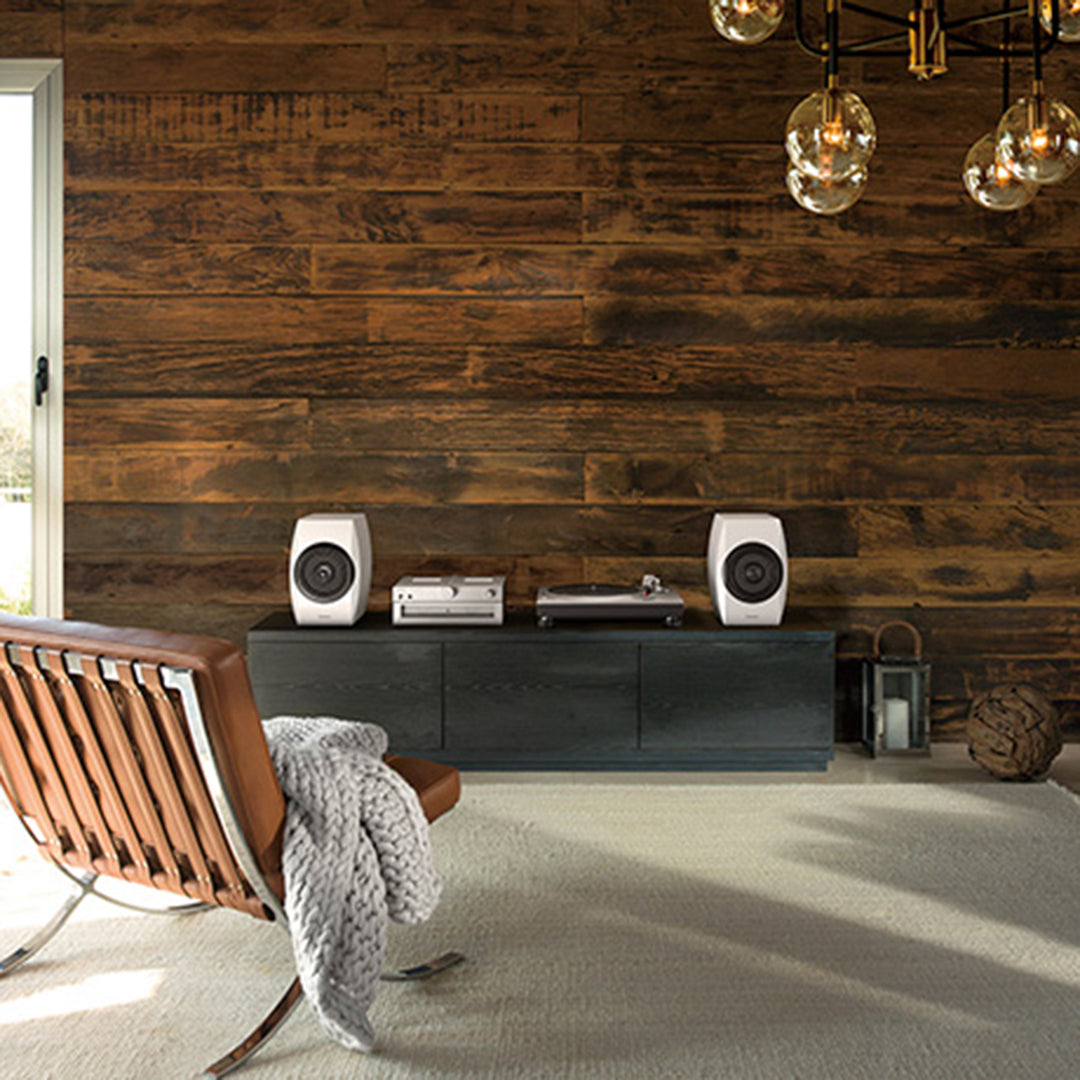 Technics Premium Class SL-1500C Direct Drive Turntable in silver sitting on a tv unit in a living room beside booshelf speakers